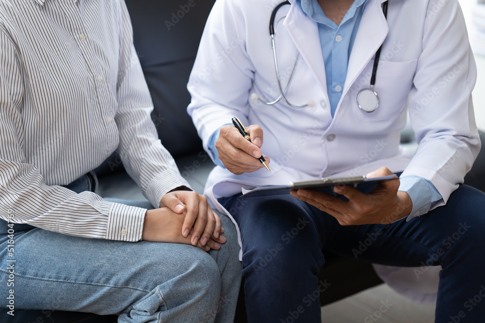 Doctor and patient sitting and talking at medical examination at hospital office, close-up. Therapis