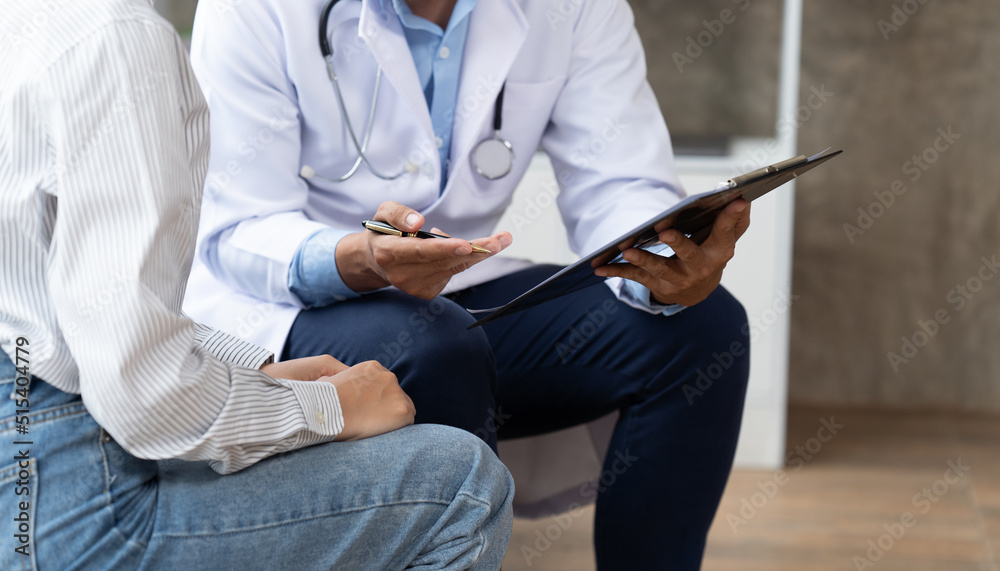 Doctor and patient sitting and talking at medical examination at hospital office, close-up. Therapis