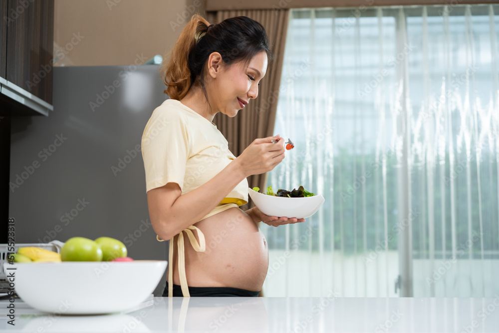 亚洲美女孕妇在家厨房吃健康食品。