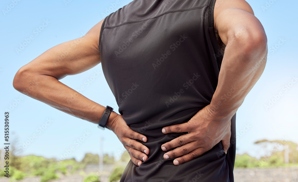 Rearview of athlete with back pain. Closeup back view of an uncomfortable young sportsman standing o