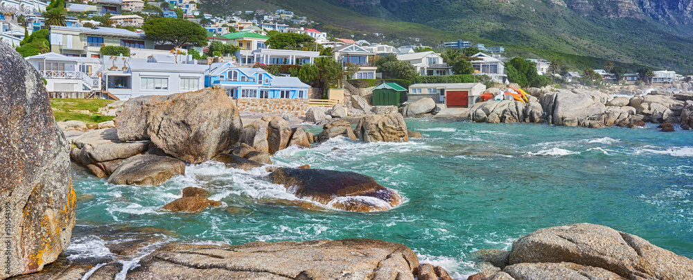 南非开普敦坎普斯湾海滩的海景、岩石和住宅楼。潮汐