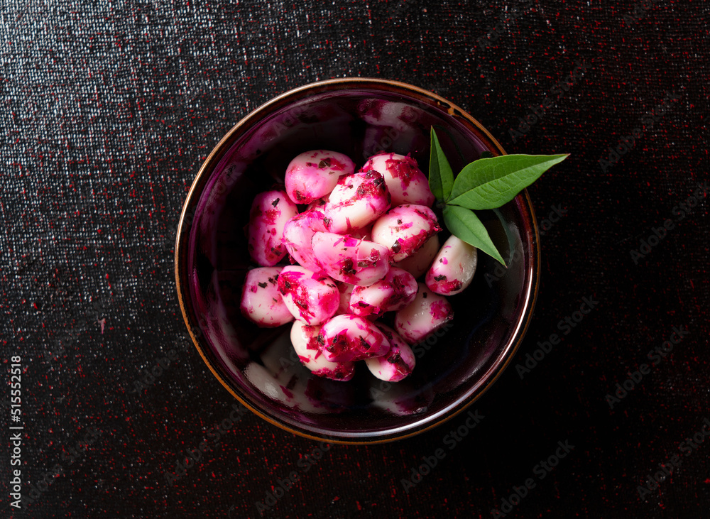 Pickled shiso garlic served on a plate placed on a black background.