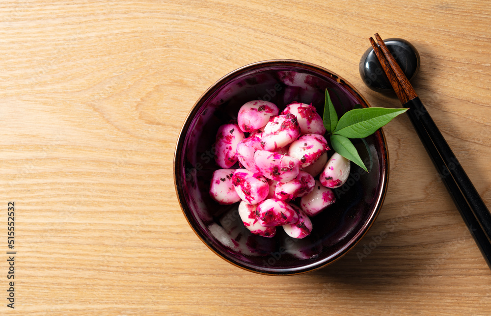 Pickled shiso bonito garlic on a plate placed against a wooden background.