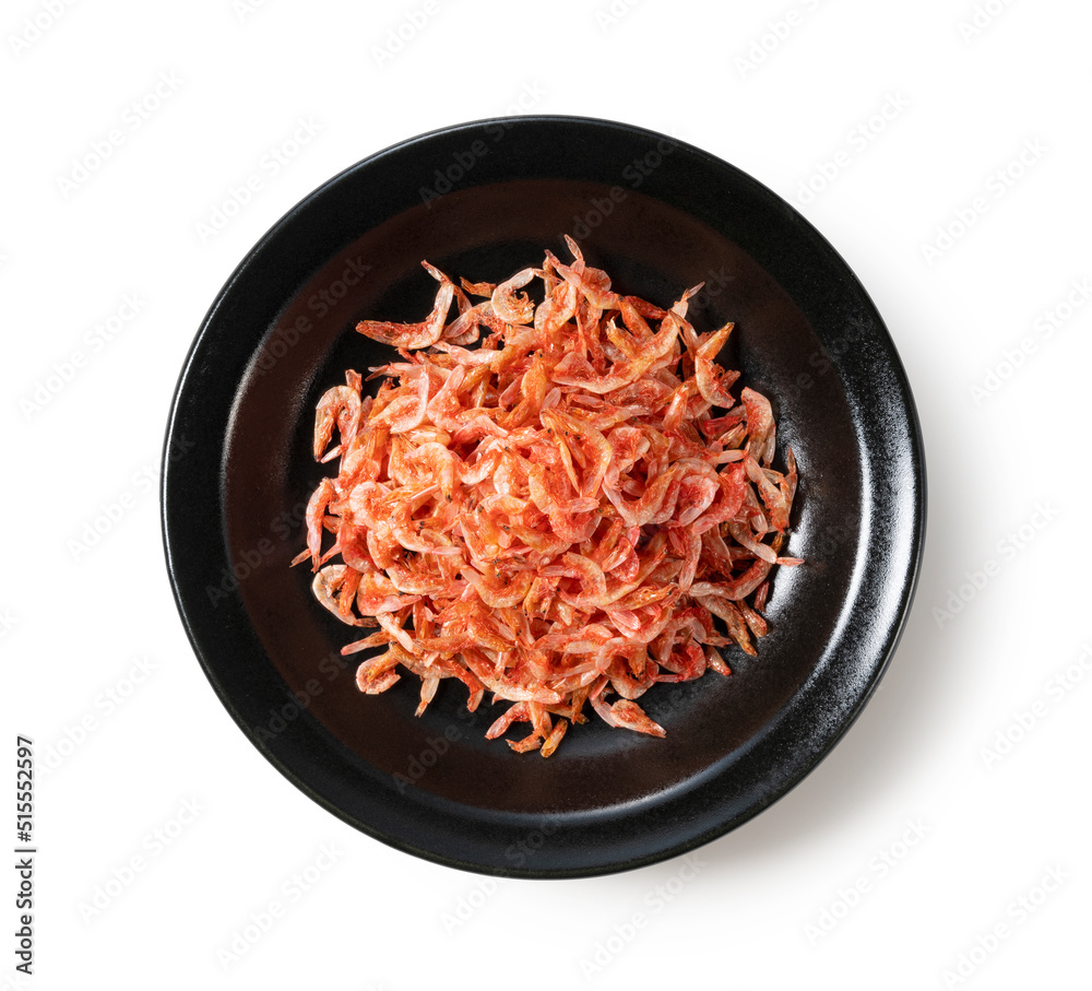 Dried sakura shrimps on a plate placed on a white background.