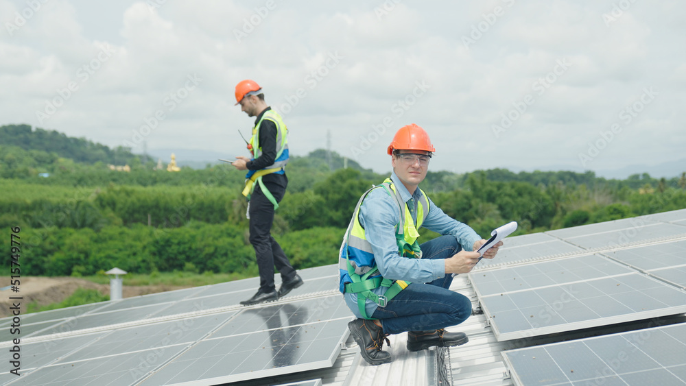 工程师和建筑工人正在检查屋顶上的太阳能电池板。