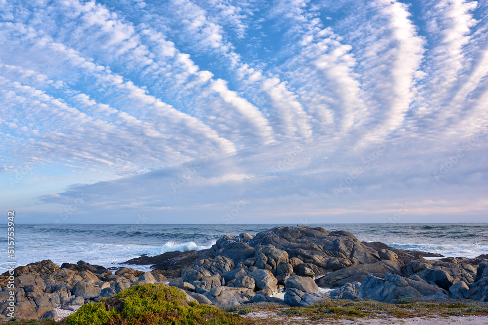 Copyspace at sea with a cloudy blue sky background and rocky coast in Western Cape South Africa. Oce