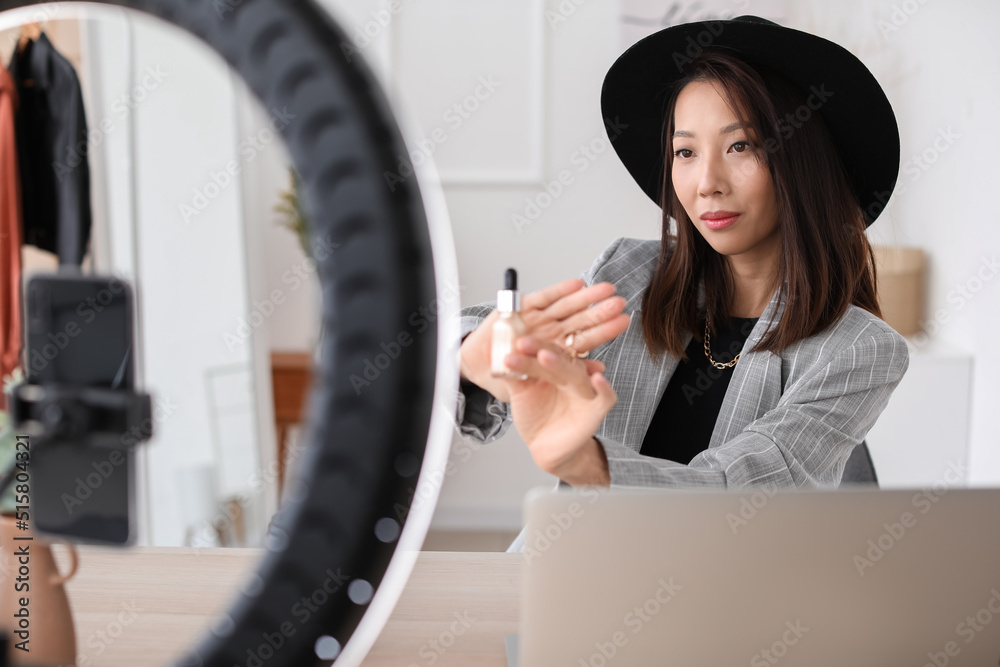 Female Asian beauty blogger with cosmetics recording video in studio