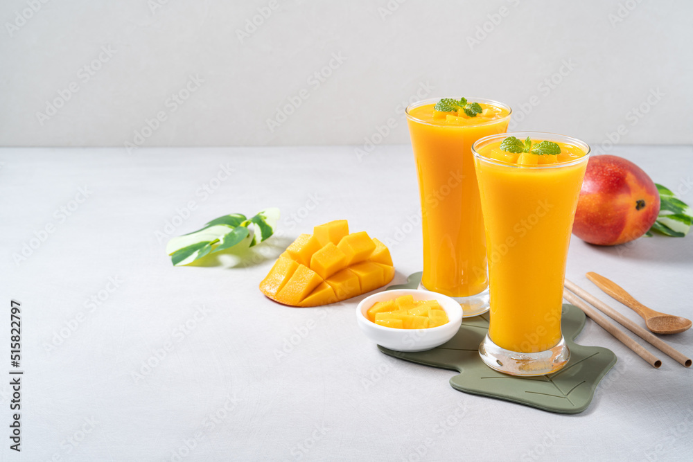 Fresh beautiful delicious mango juice smoothie in glass cup on gray table background.