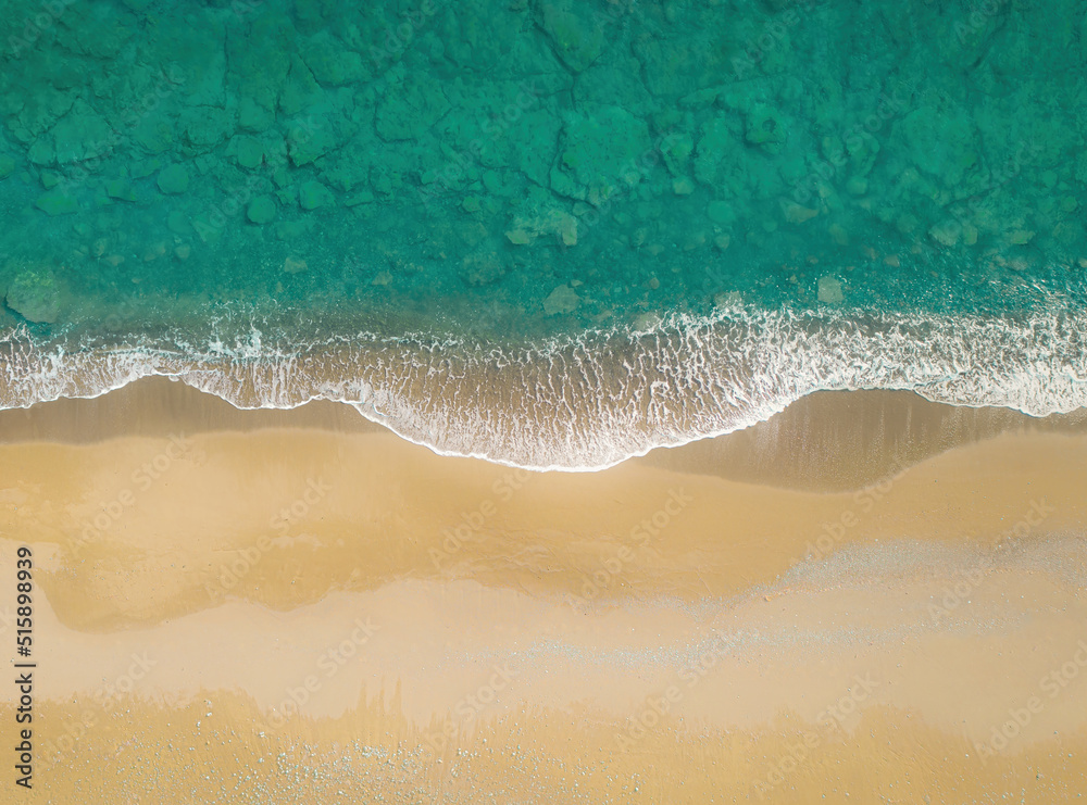 金色沙滩上绿色的海浪破碎。正上方俯视图，自然背景