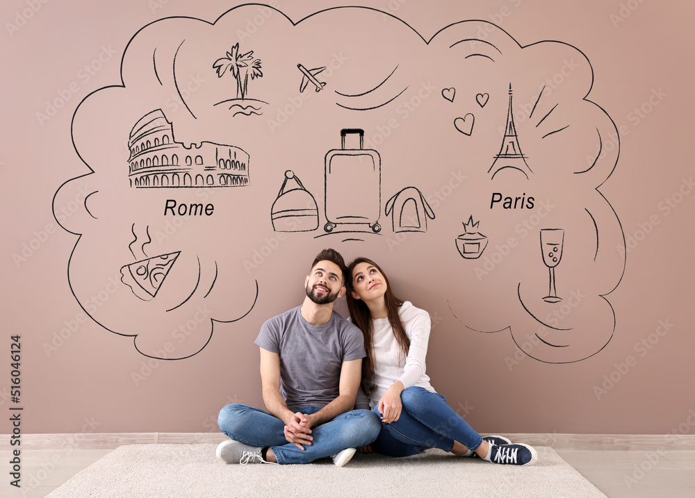 Young couple dreaming about their new journey near color wall in room