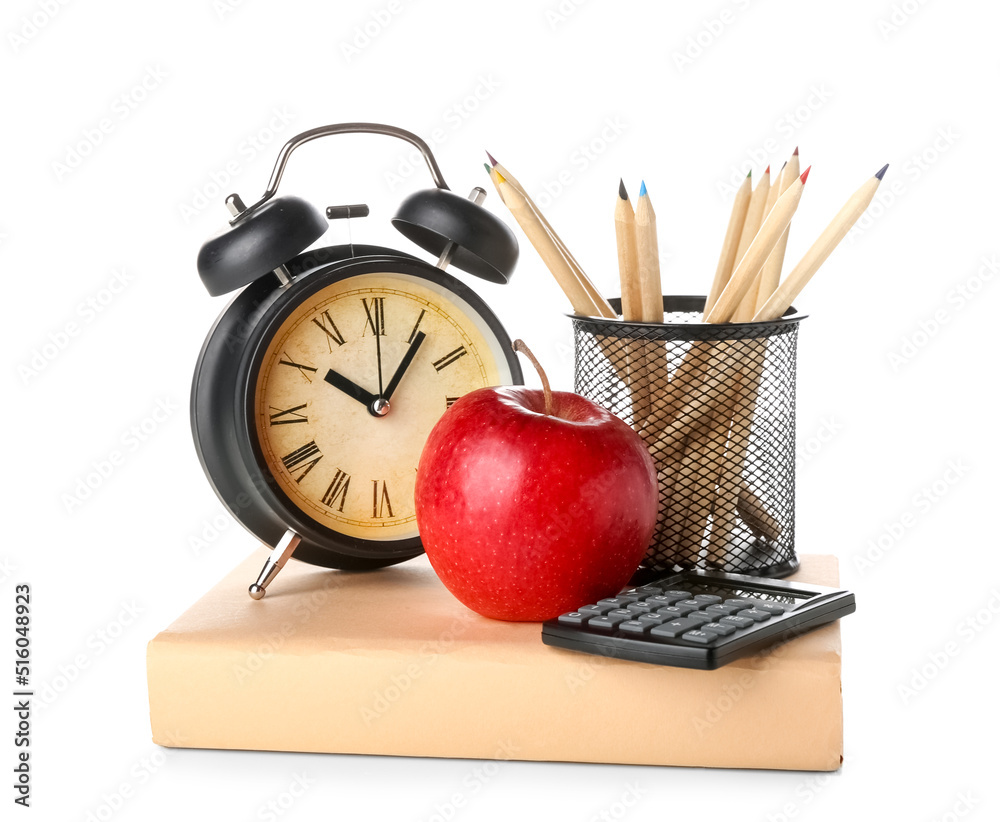 Book with apple, pencils, calculator and alarm clock on white background