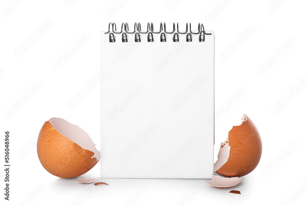 Blank notebook with broken egg shell on white background