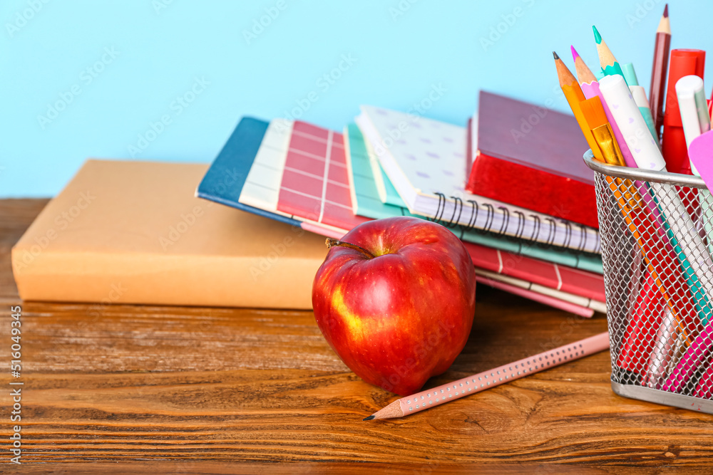 School stationery with apple on table against blue background