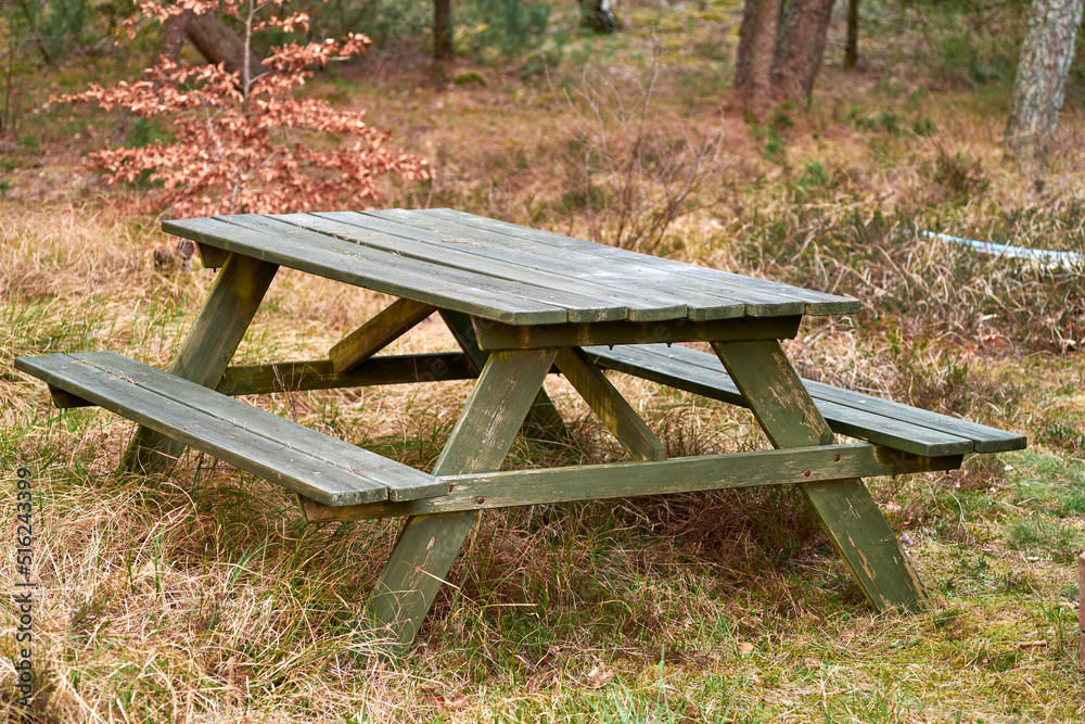 Wooden bench and table in a remote meadow for a picnic in the forest outside. Seating furniture in a