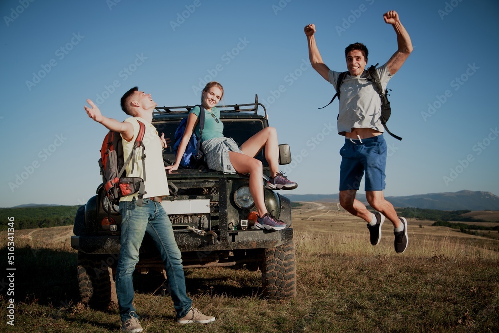 Young happy adult friends on a hike with a car