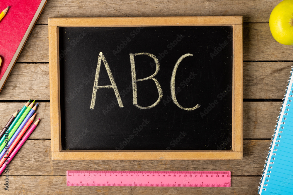 Composition of blackboard with abc and school items on wooden background