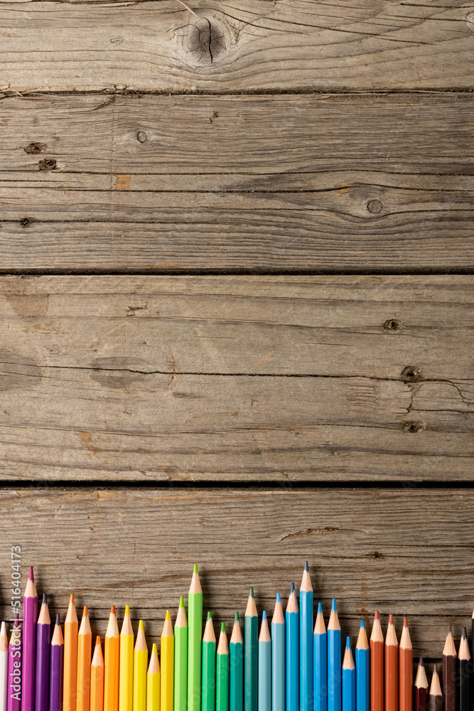 Vertical composition of colorful crayons on wooden background