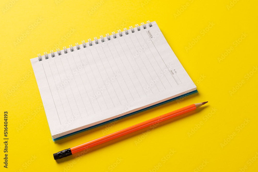 Composition of notebook with copy space and pencil on yellow surface