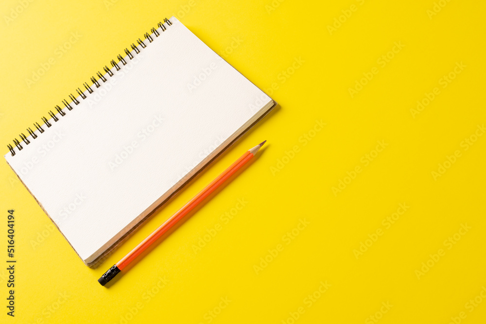 Composition of notebook with copy space and pencil on yellow surface