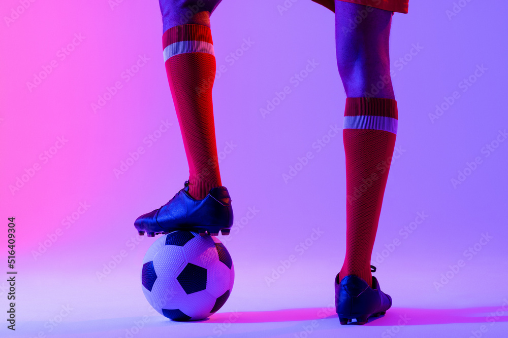 African american male soccer player with football over neon pink lighting