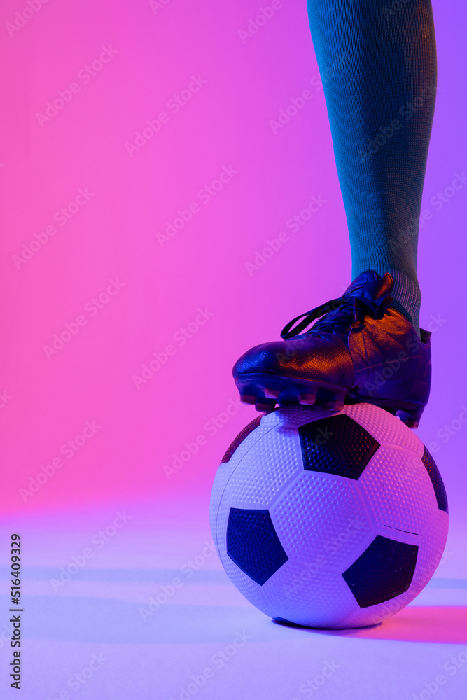 Male soccer player with football over neon pink lighting