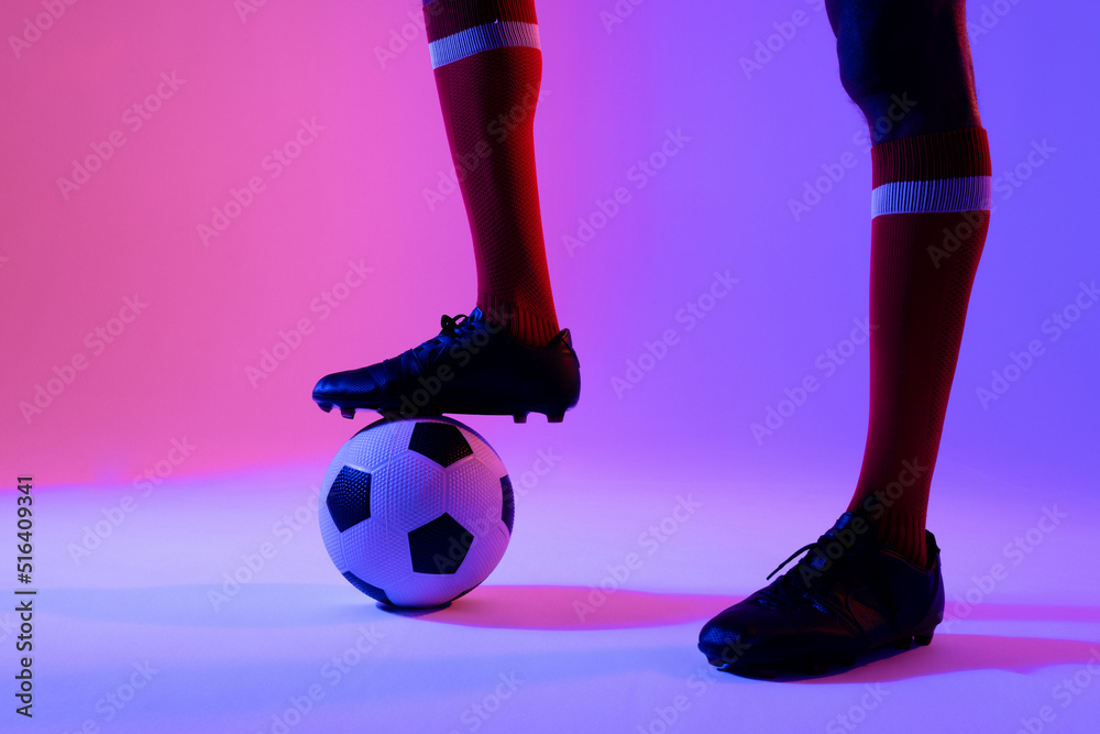 African american male soccer player with football over neon pink lighting