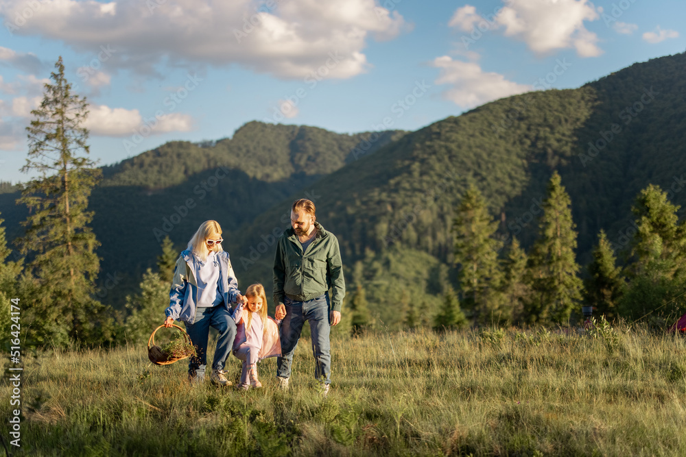 Young caucasian couple with little girl walk together while traveling in the mountains. Happy family