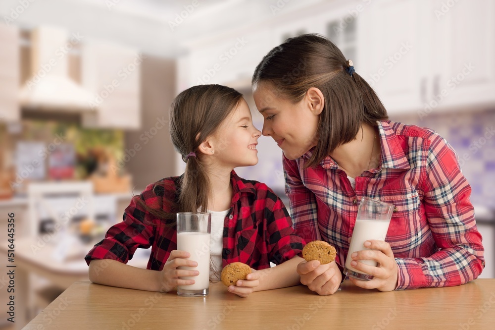 Happy Family Mother And Daughter Holding Glasses While Sitting Together In Kitchen, Enjoying Healthy