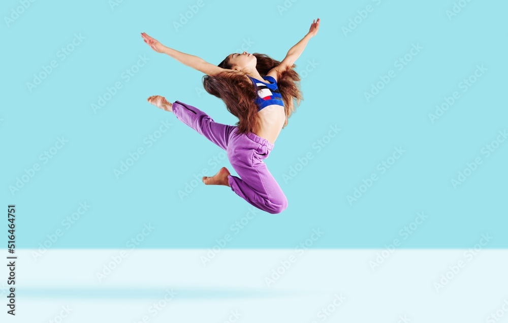 Concentrated athletic girl jumping during running. Modern healthy and sports youngster lifestyle.