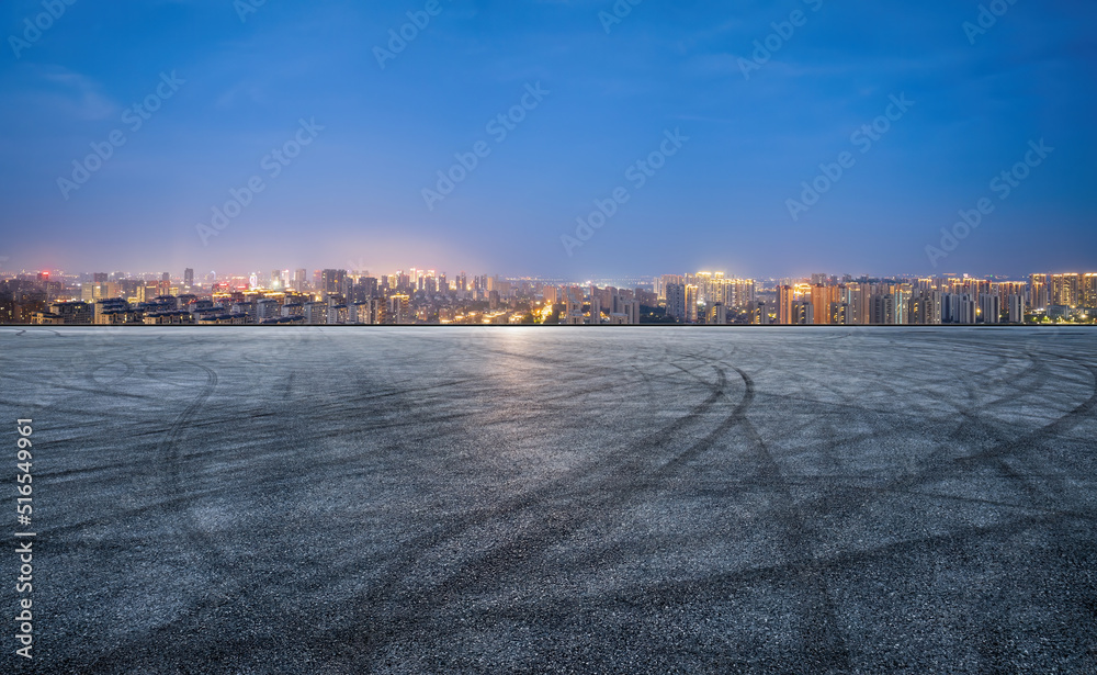 沥青路和现代城市天际线的夜景。高角度视角。