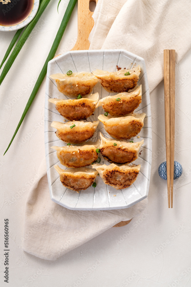 在白桌子背景上，用酱油在盘子里煎饺子饺子饺子。