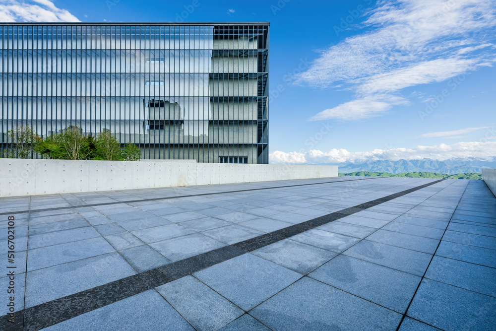 Empty square floor and modern commercial building with mountain background