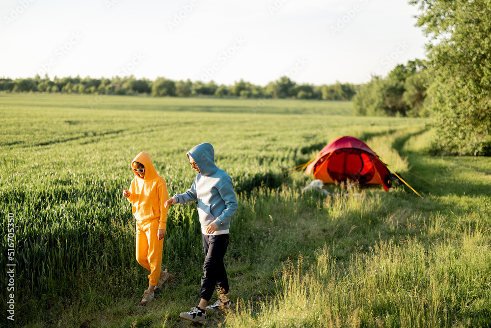 年轻夫妇在夏天带着帐篷在绿地上旅行时，一起散步和聊天，玩得很开心