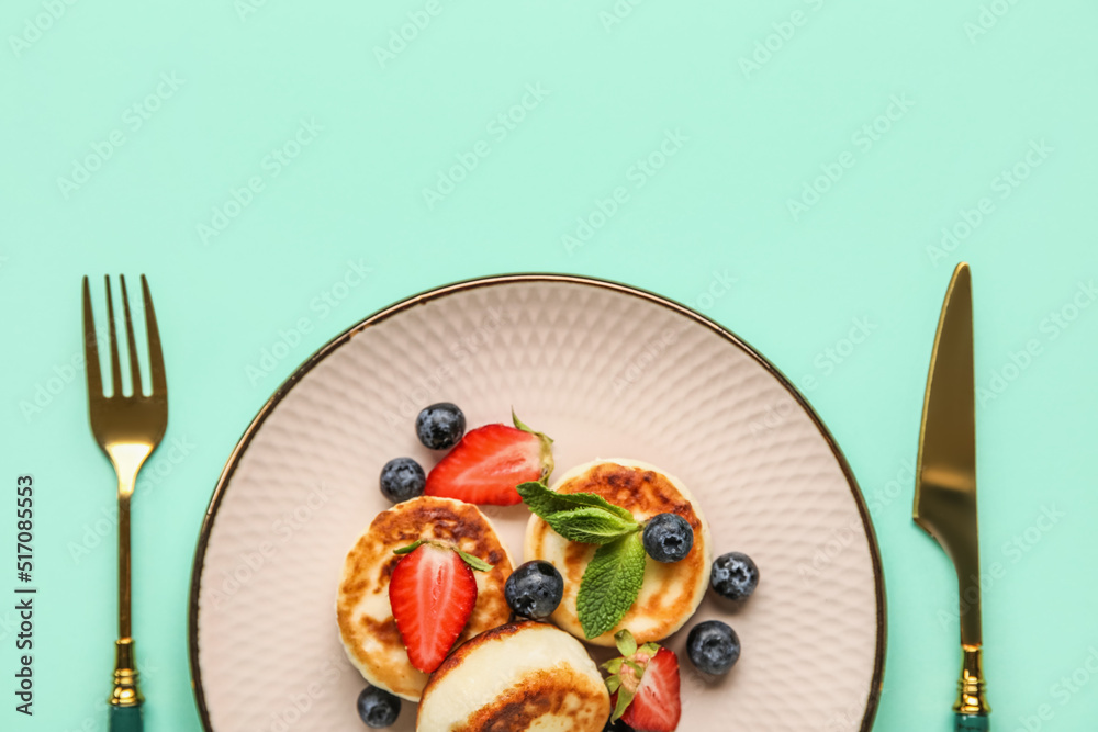 Plate with cottage cheese pancakes, berries and mint leaves served on color background, closeup