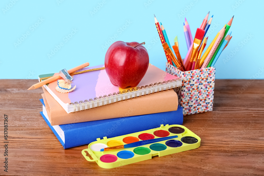 School stationery with apple on table against blue background