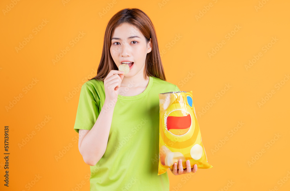 Photo of young Asian girl eating snack on background