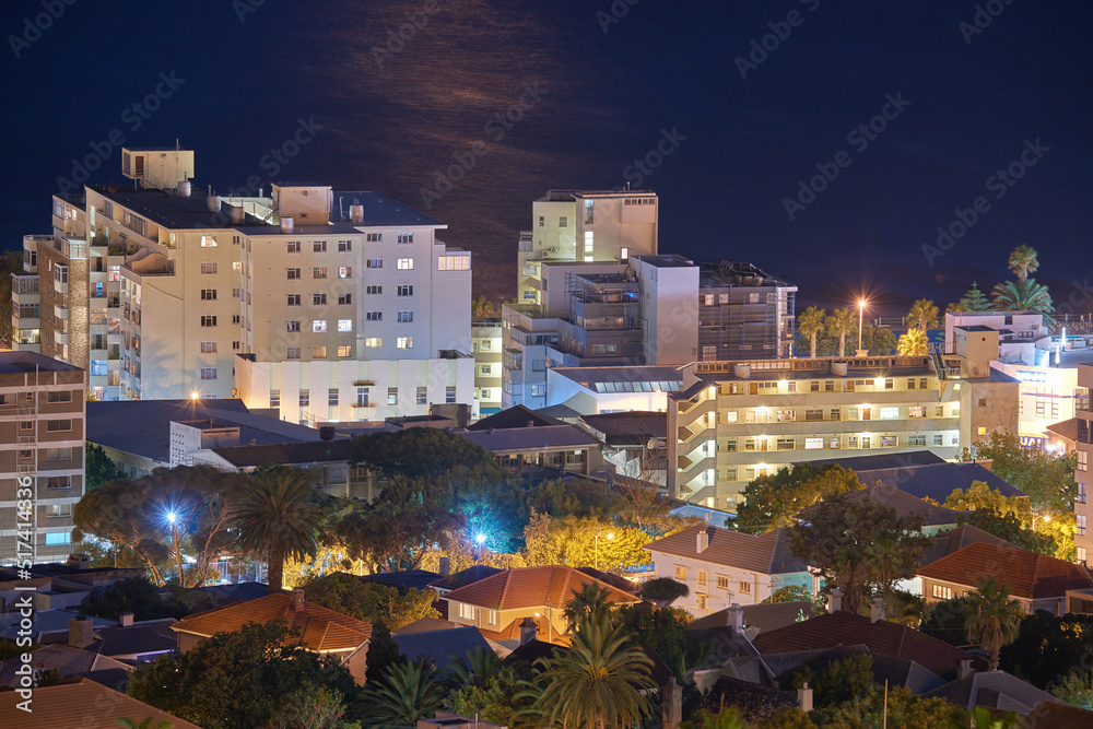 带电灯、基础设施和大海或海洋背景的城市建筑的夜景