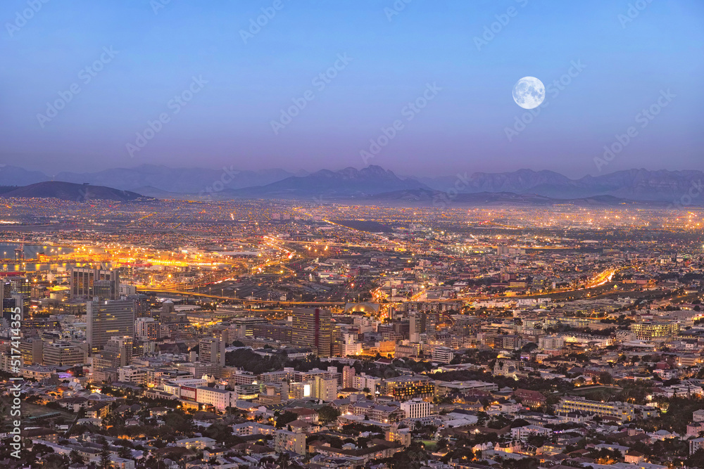 Copy space night view of city buildings with electricity lights, infrastructure and moon with mounta