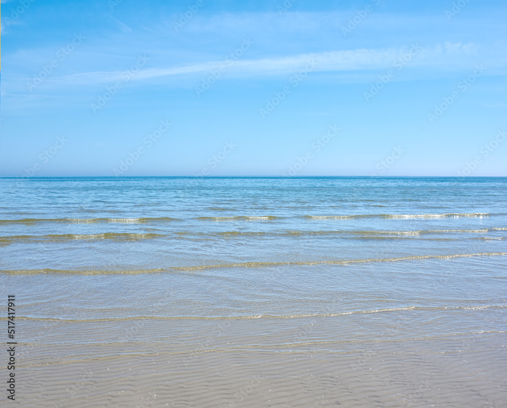 Sea and ocean view of waves washing onto an empty and relaxing tropical beach on a warm, summer day.