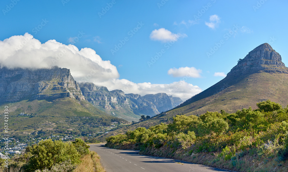 A road along a mountain and green nature with a cloudy blue sky and copy space. Beautiful landscape 