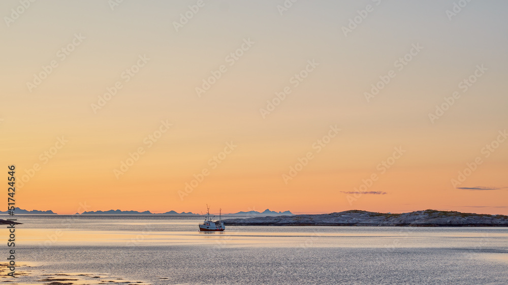 Distant sailboat in the sea near a mountain in the water during sunset. The ocean, beach, or large l