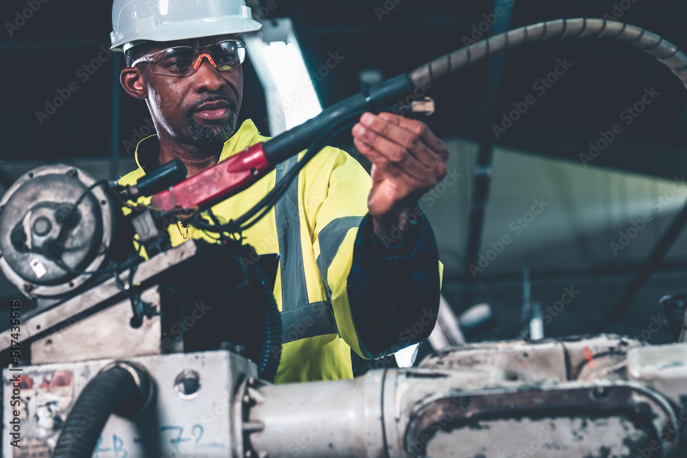 African American factory worker working with adept robotic arm in a workshop . Industry robot progra