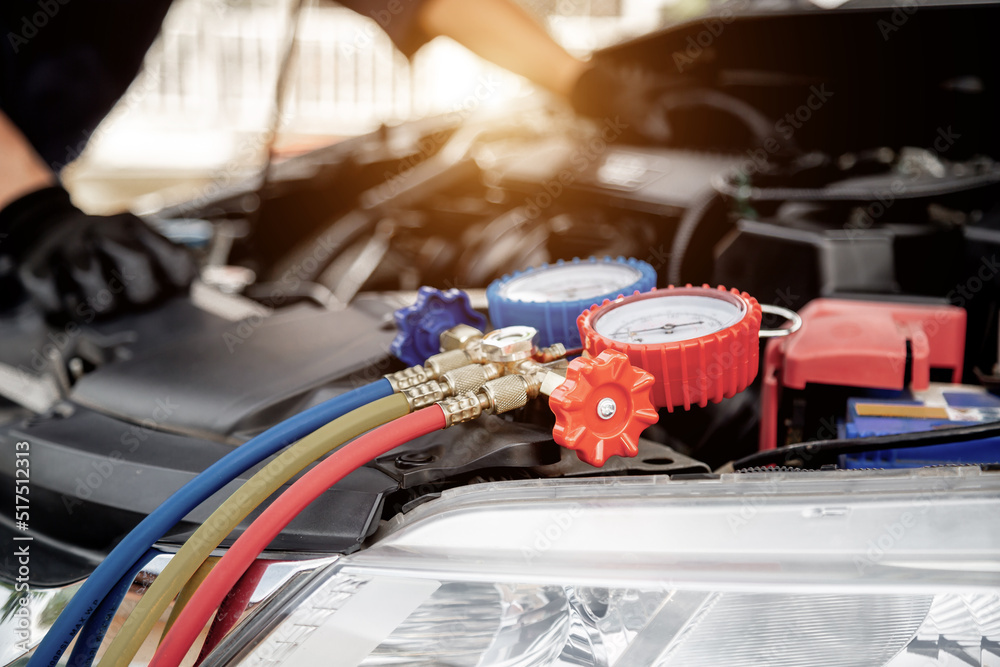 Close up hand of auto mechanic using measuring manifold gauge check the refrigerant and filling car 