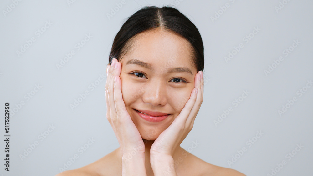 Portrait young Asian woman touching healthy facial beauty skin over grey background.