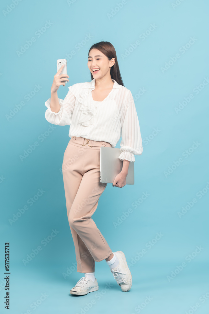 Young beautiful asian woman with smart casual cloth use smartphone isolated on blue background