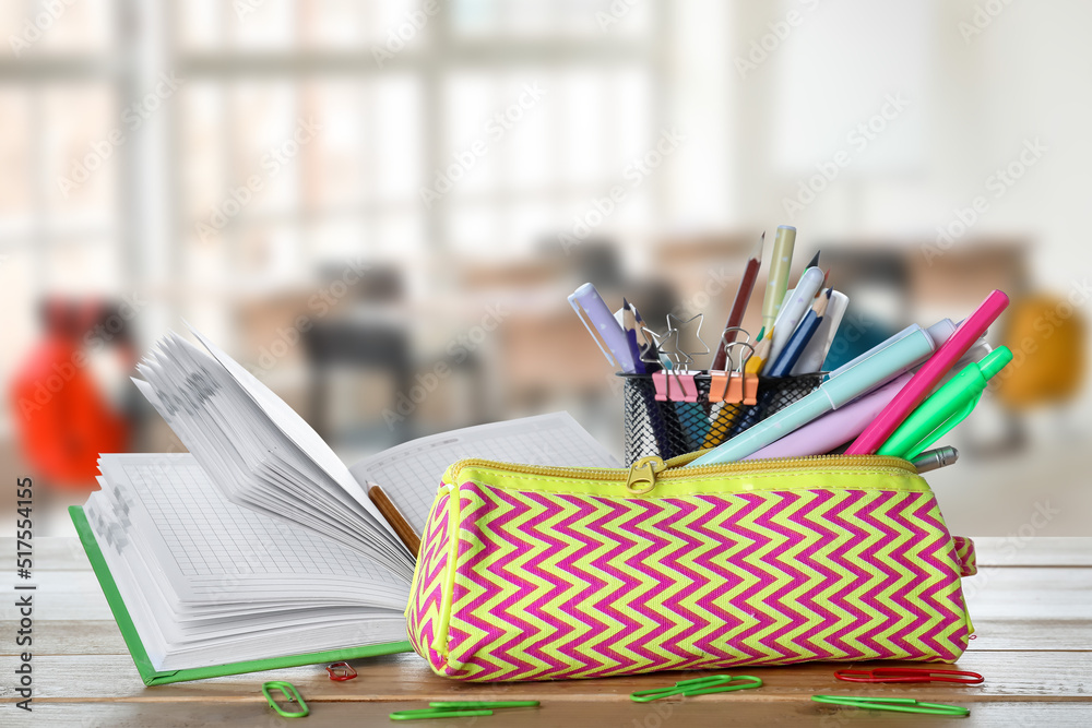 Set of school supplies on table in classroom