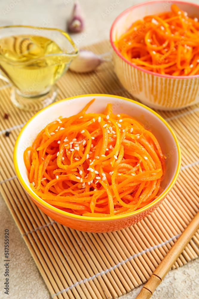 Bowls with tasty korean carrot salad on table, closeup