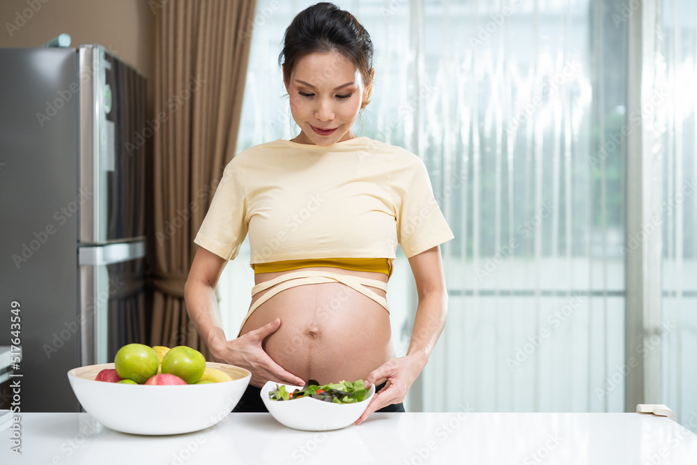 亚洲美女孕妇在家厨房吃健康食品。