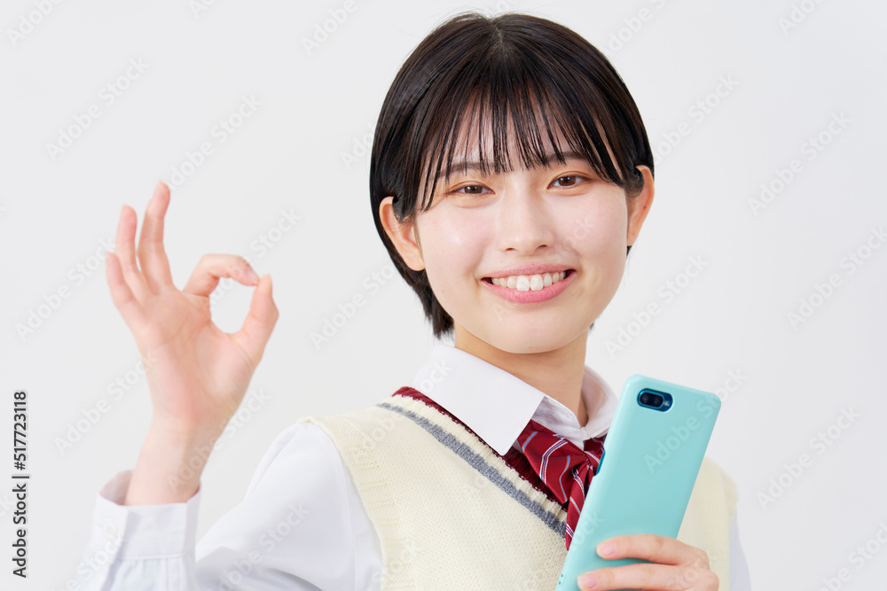 スマホを持ってOKポーズする女子高生　白背景