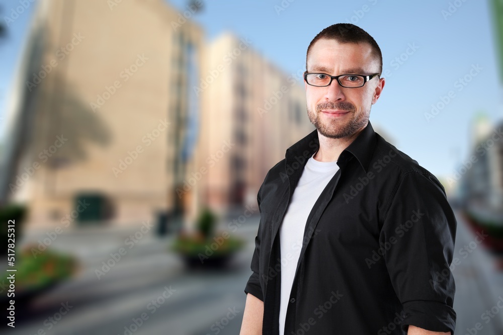 Authentic young handsome man standing on the street. Smiling student in university campus. Education